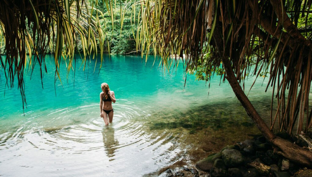 Female tourist in blue water lagoon of Portland, Jamaica